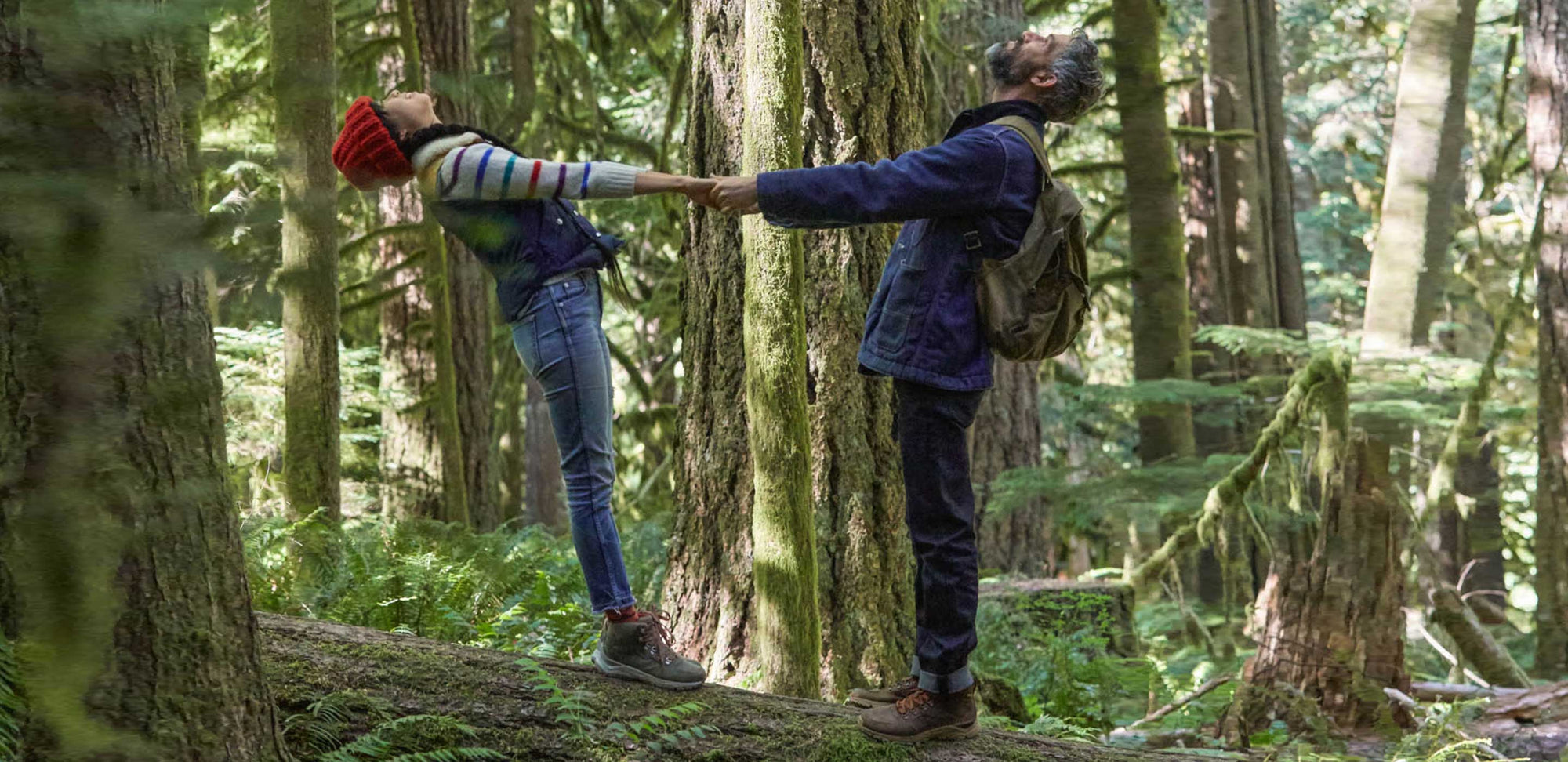 A couple in the forest holding hands and looking up